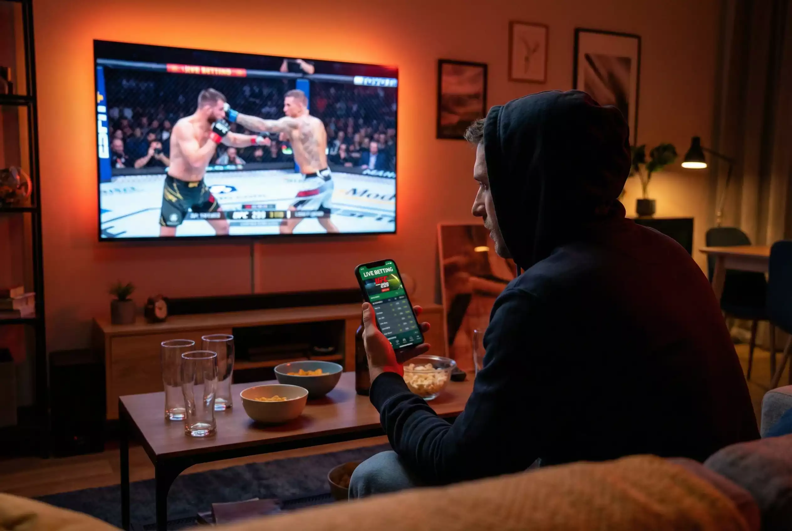 UFC Live-Wetten: Person verfolgt MMA-Kampf auf Bildschirm mit Smartphone für Echtzeit-Wetten